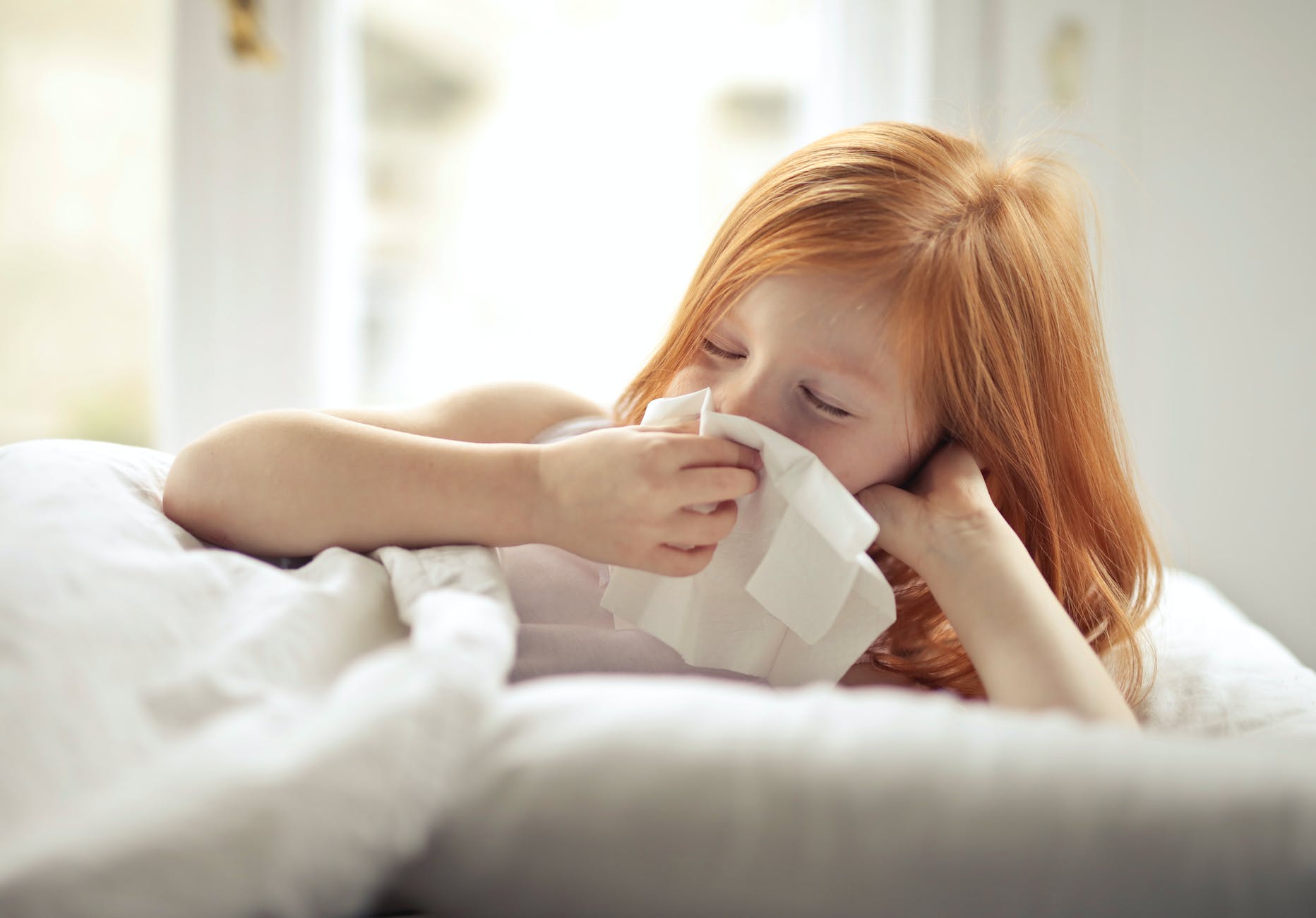 a sick girl wiping her nose with tissue