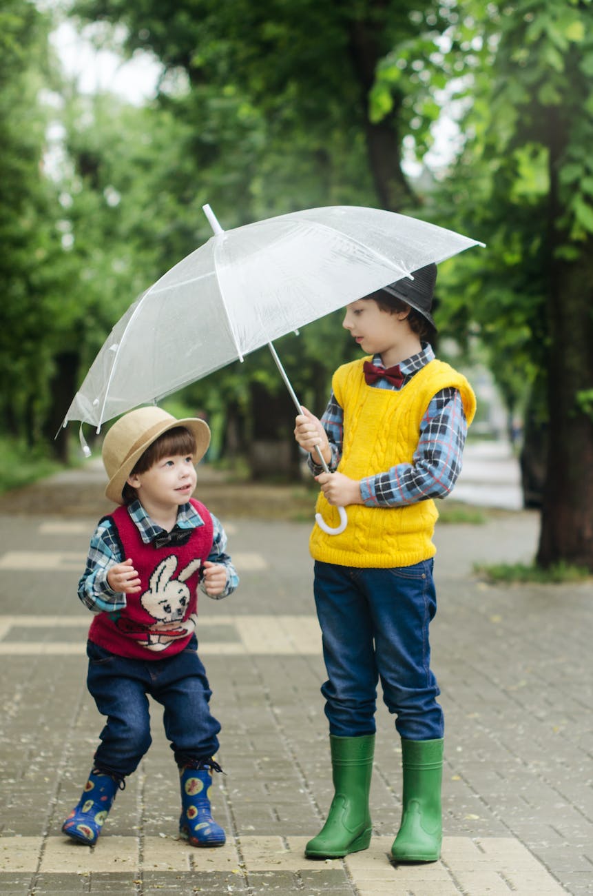 toddler holding umbrella beside girl