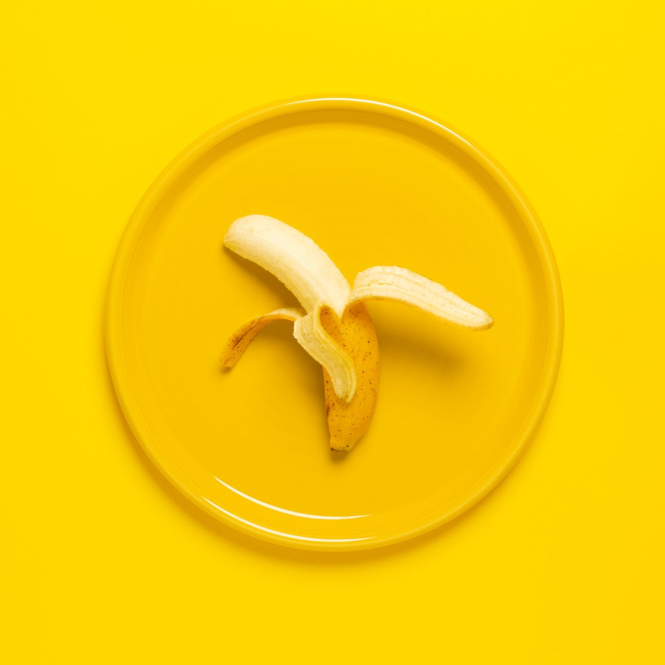 photo of peeled banana on yellow plate and background